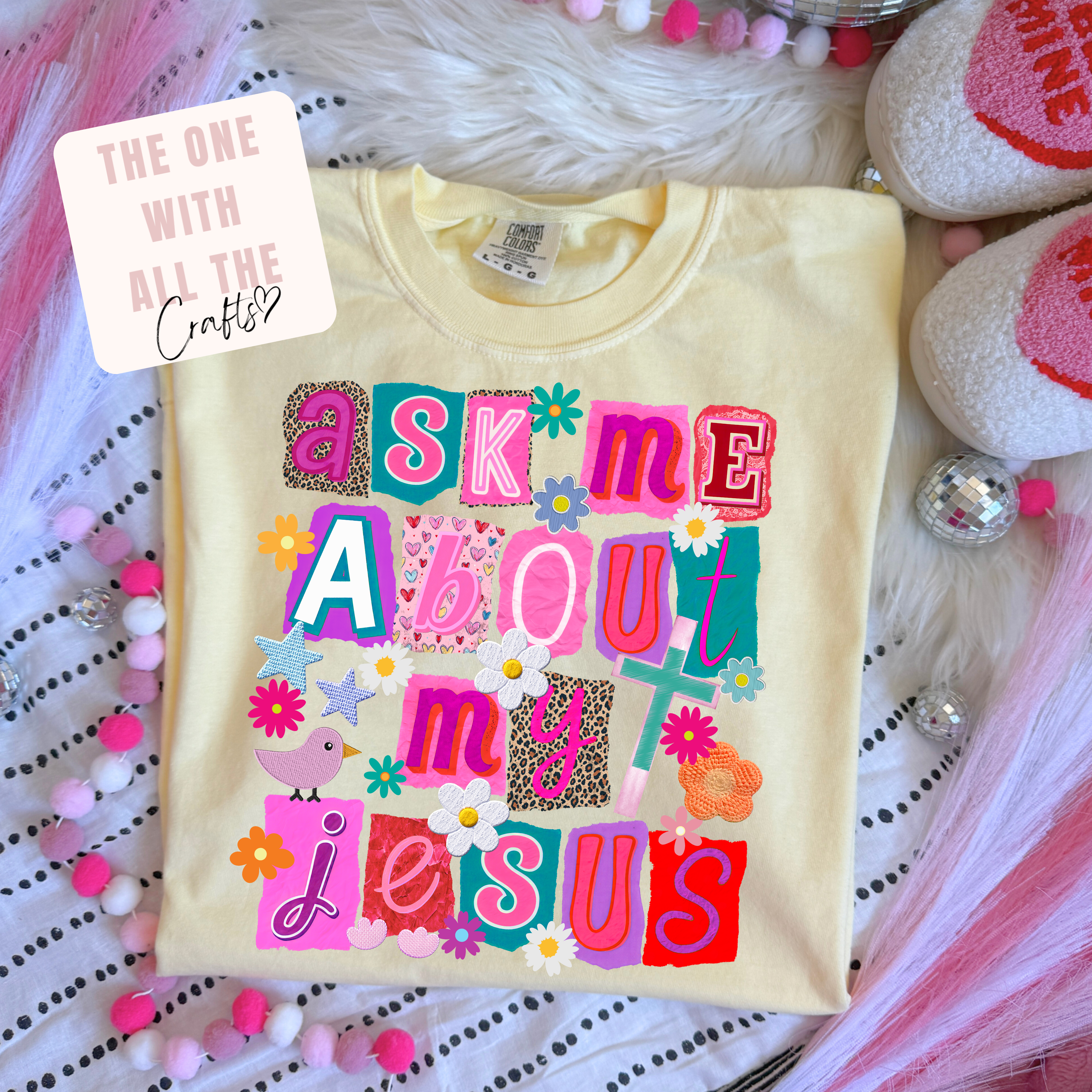 Beige t-shirt with colorful text 'Ask me about my Jesus' on a decorative background