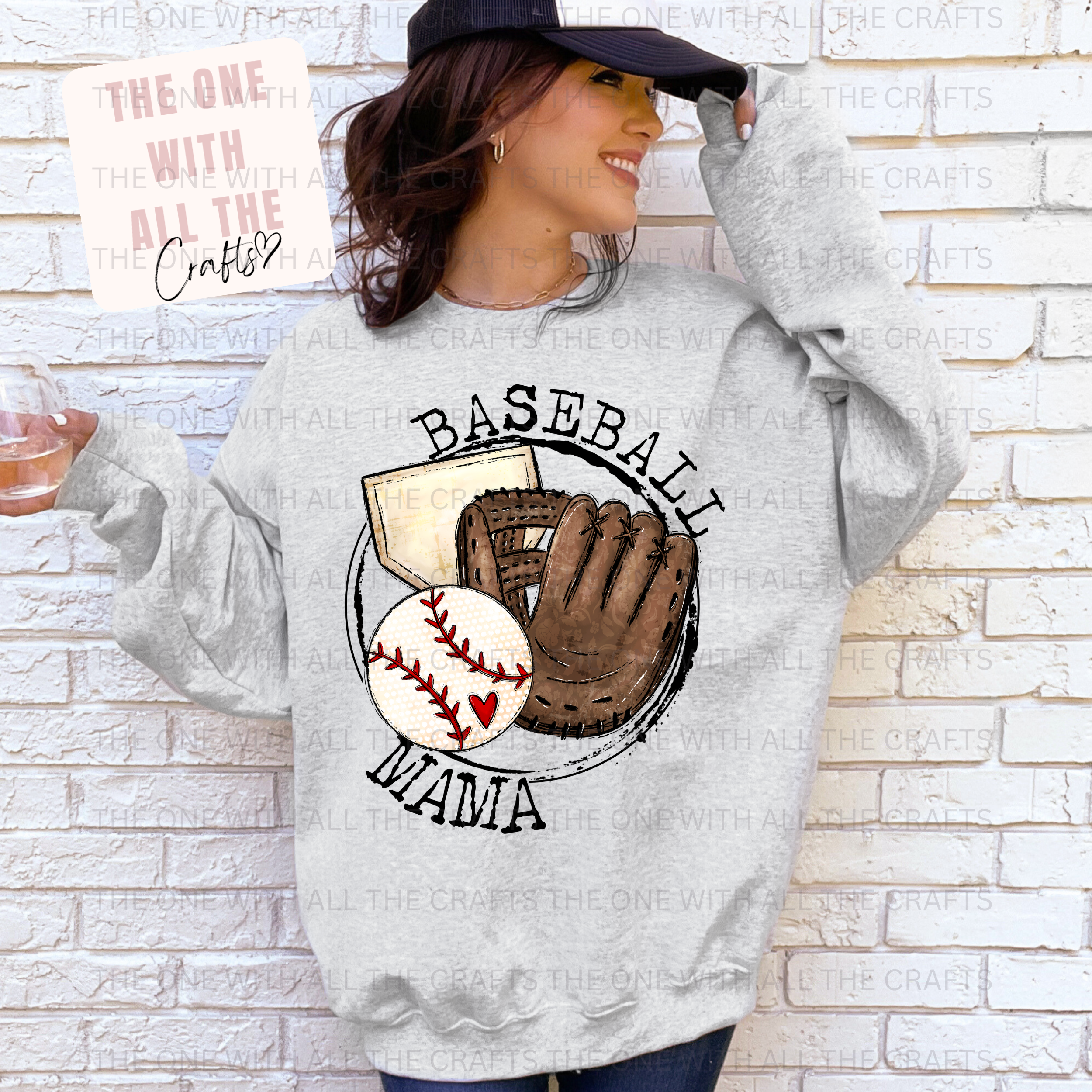 Person wearing a gray sweatshirt with 'Baseball Mama' design against a white brick wall.