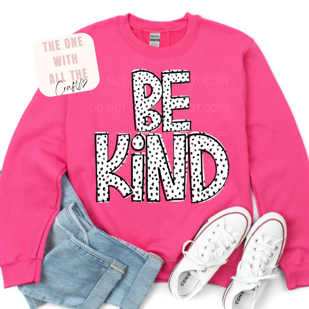 Pink sweatshirt with 'BE KIND' text, jeans, and white sneakers on a white background