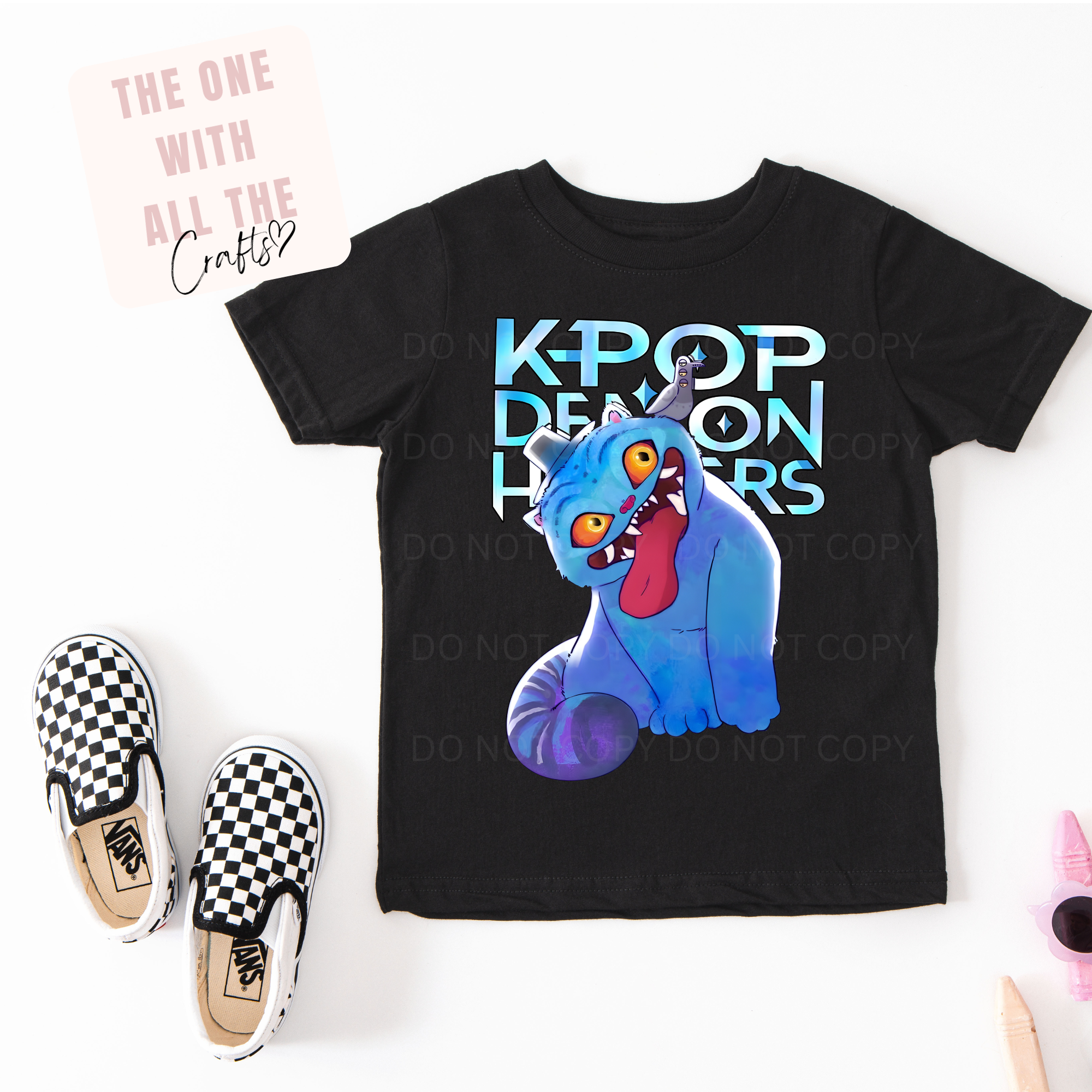 Black t-shirt with a blue creature graphic and 'K-Pop Demon Hunters' text, paired with checkered shoes on a white background.