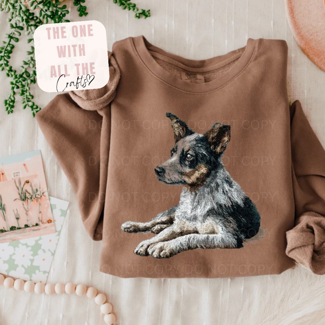 Brown sweatshirt with a dog graphic on a light wooden surface.
