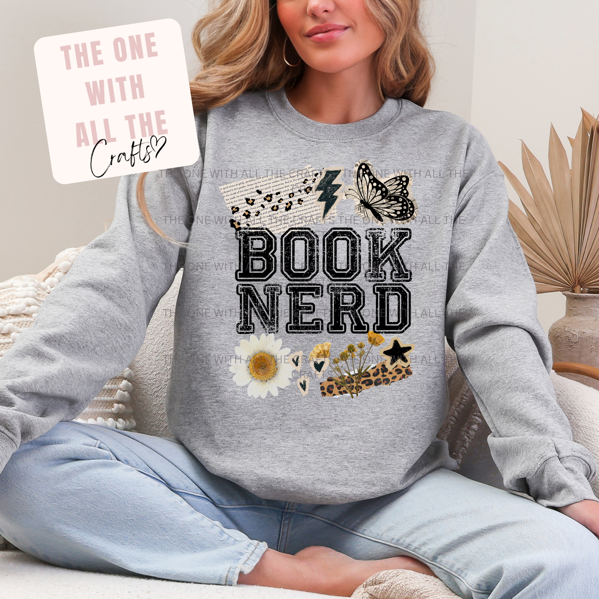 Person wearing a gray sweatshirt with 'BOOK NERD' text and decorative elements, sitting on a couch.