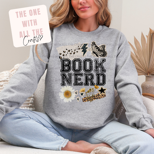 Person wearing a gray sweatshirt with 'BOOK NERD' text and decorative elements, sitting on a couch.