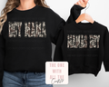 Black sweatshirts with 'BOY MAMA' and 'MAMA BOY' text, worn by a person and on a hanger.