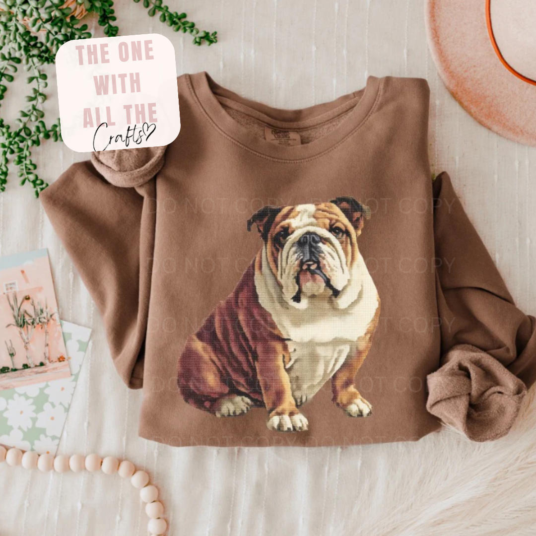 Brown sweatshirt with a bulldog graphic on a light wooden surface.
