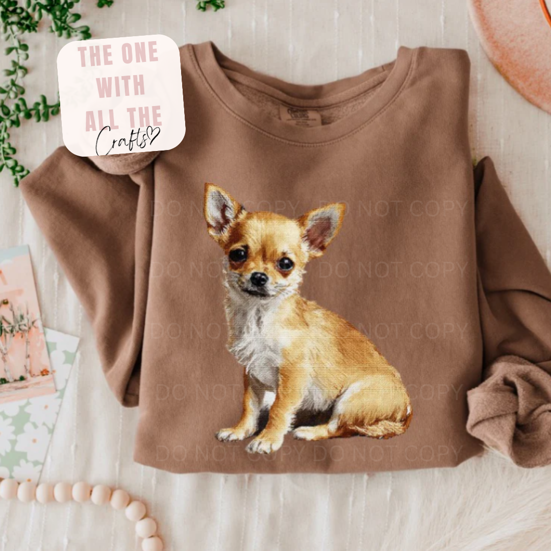 Brown sweatshirt with a chihuahua graphic on a light wooden surface.