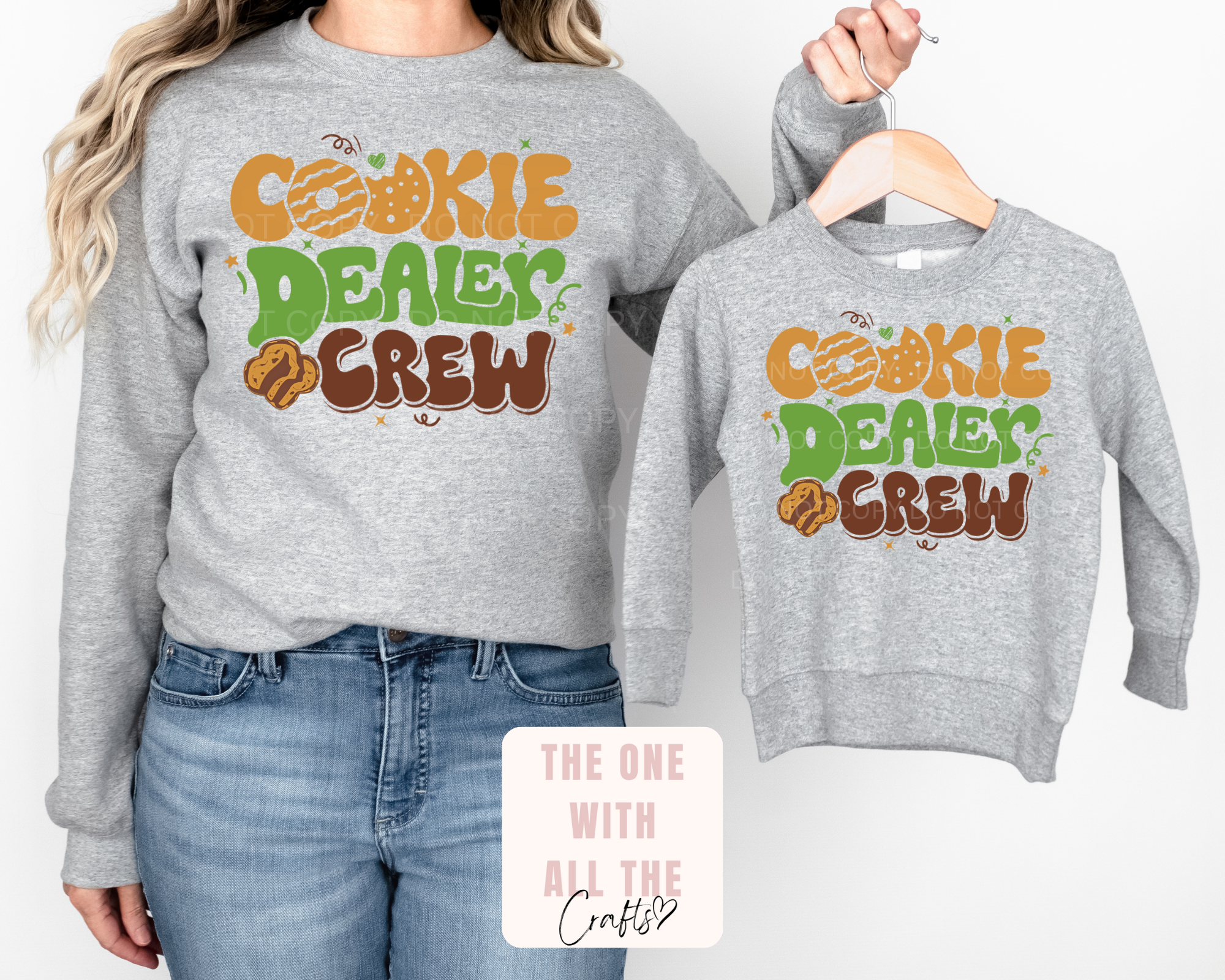 Gray sweatshirts with 'Cookie Dealer Crew' text, one worn by a person, the other on a hanger.