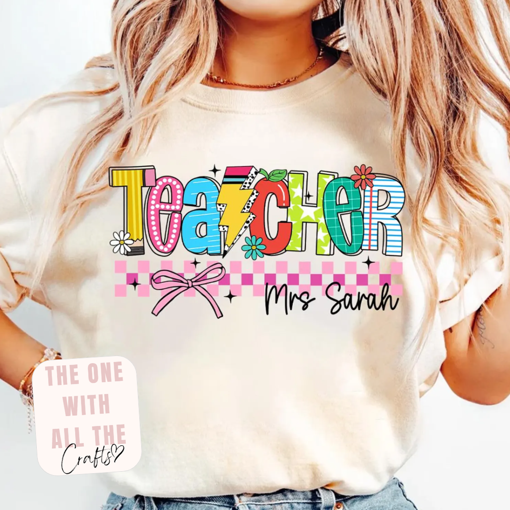 Person wearing a white t-shirt with colorful 'Teacher' text and 'Mrs Sarah' on a light background