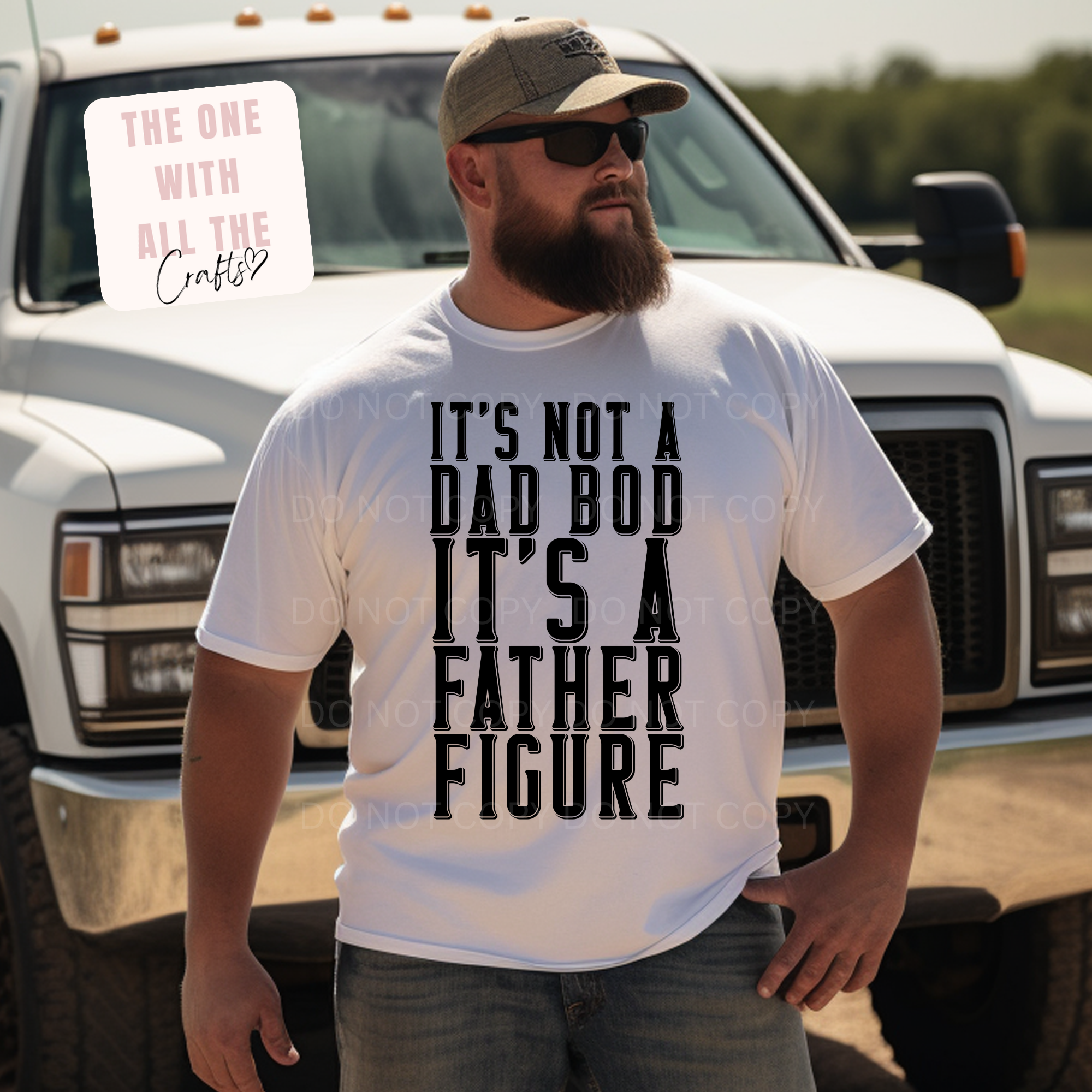 Man with beard wearing a white shirt with the words 'It's Not A Dad Bod It's A Father Figure' in front of a truck outdoors