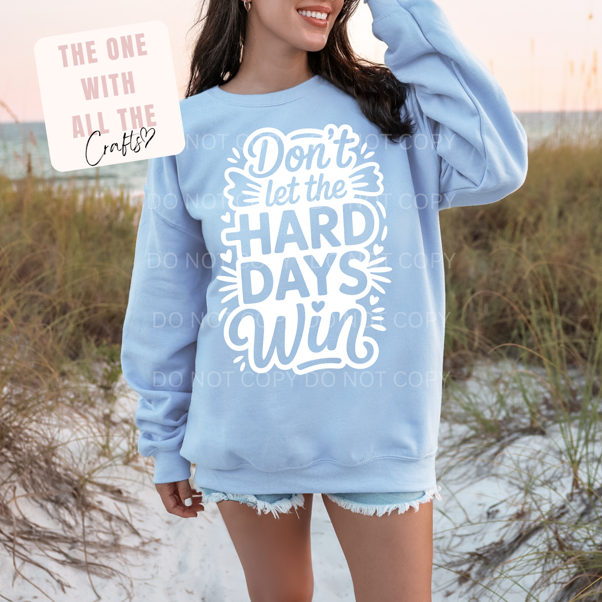 Person wearing a light blue sweatshirt with text on a beach