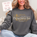 Person wearing a dark gray sweatshirt with 'Dragonfly Inn' logo, sitting on a couch.
