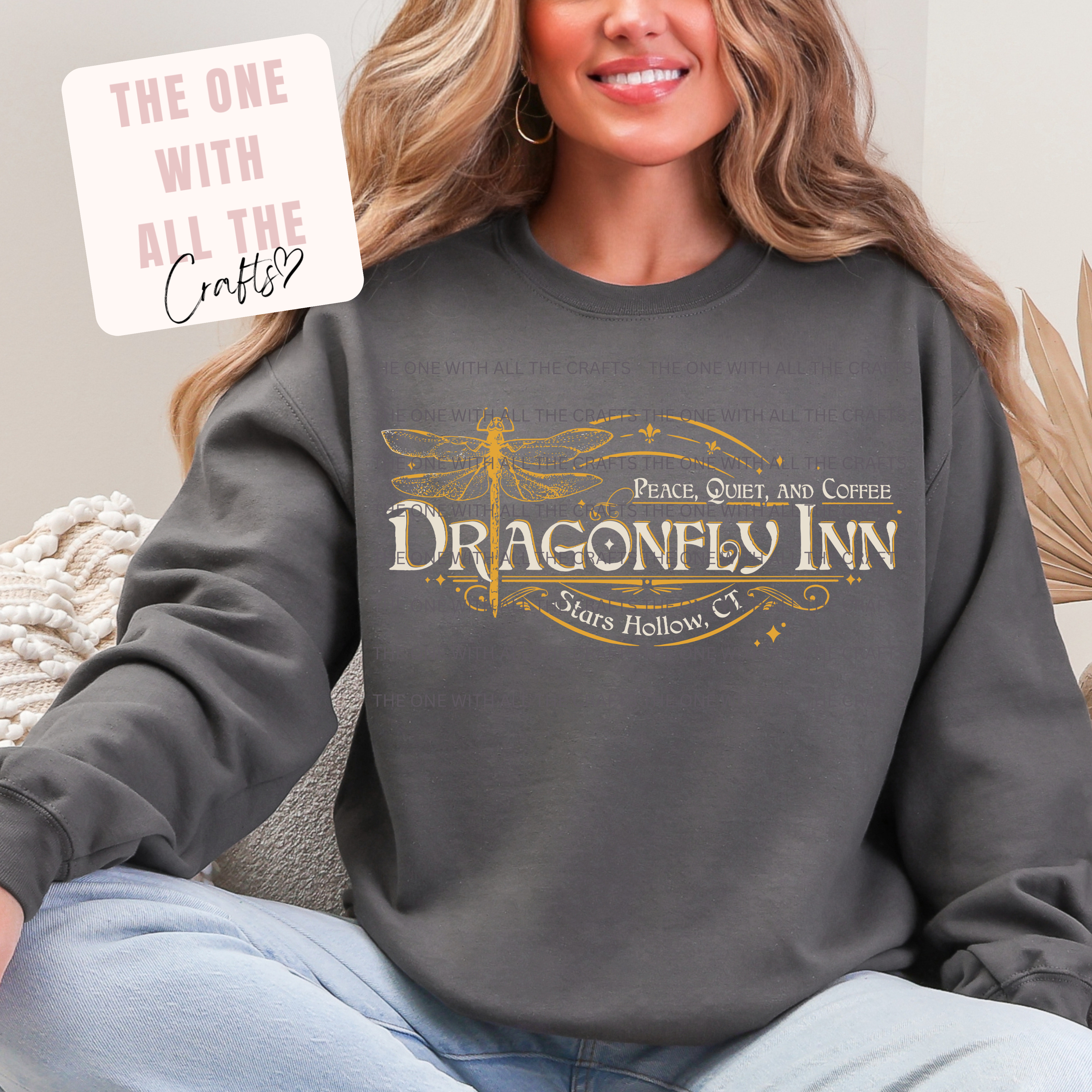 Person wearing a dark gray sweatshirt with 'Dragonfly Inn' logo, sitting on a couch.