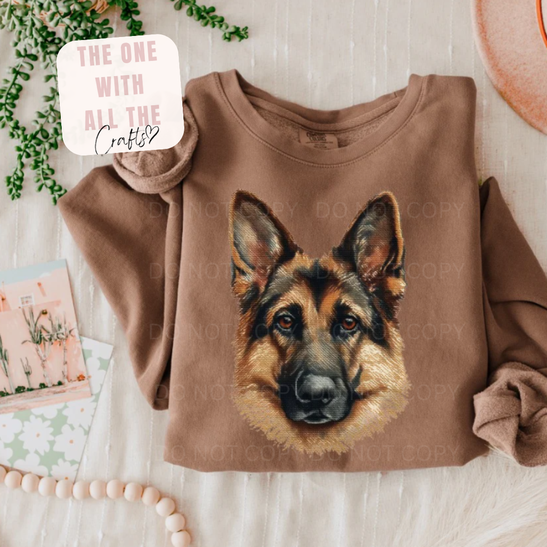 Brown sweatshirt with a German Shepherd design on a light wooden surface.