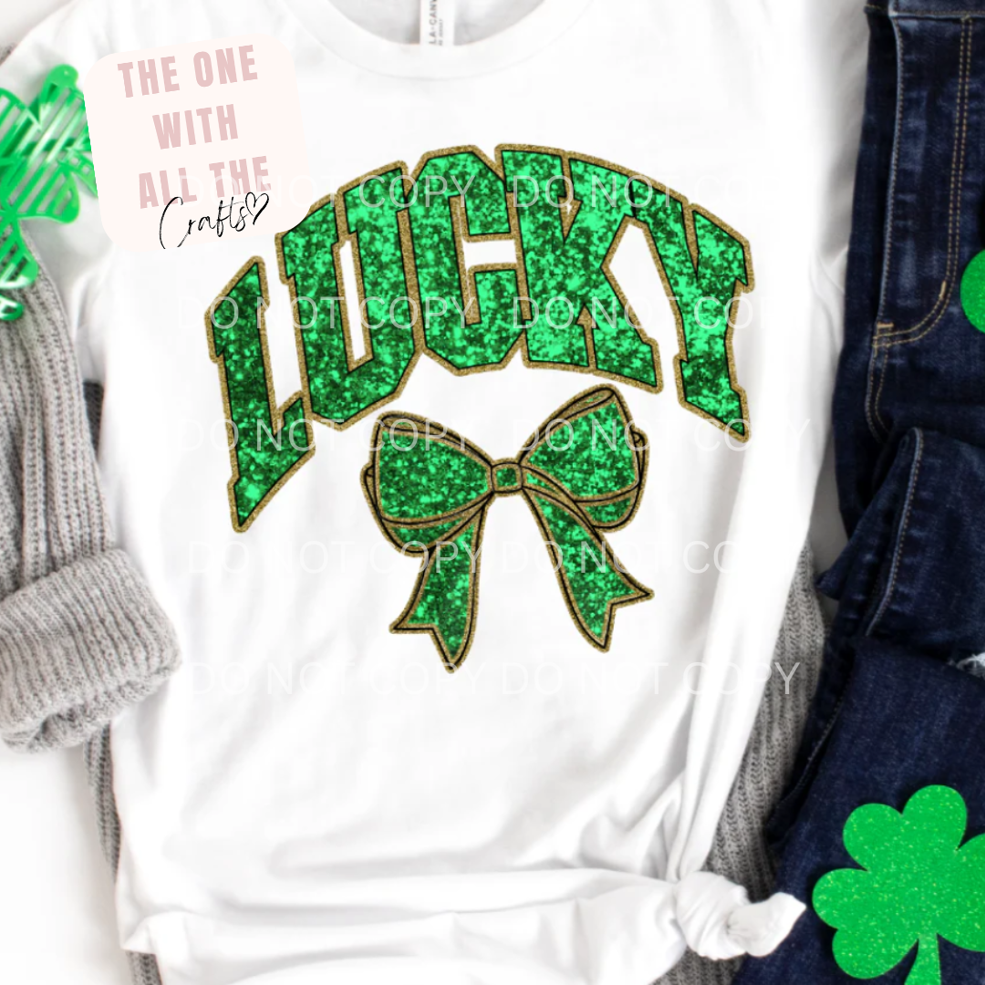 White shirt with green 'LUCKY' text and bow design, surrounded by accessories.