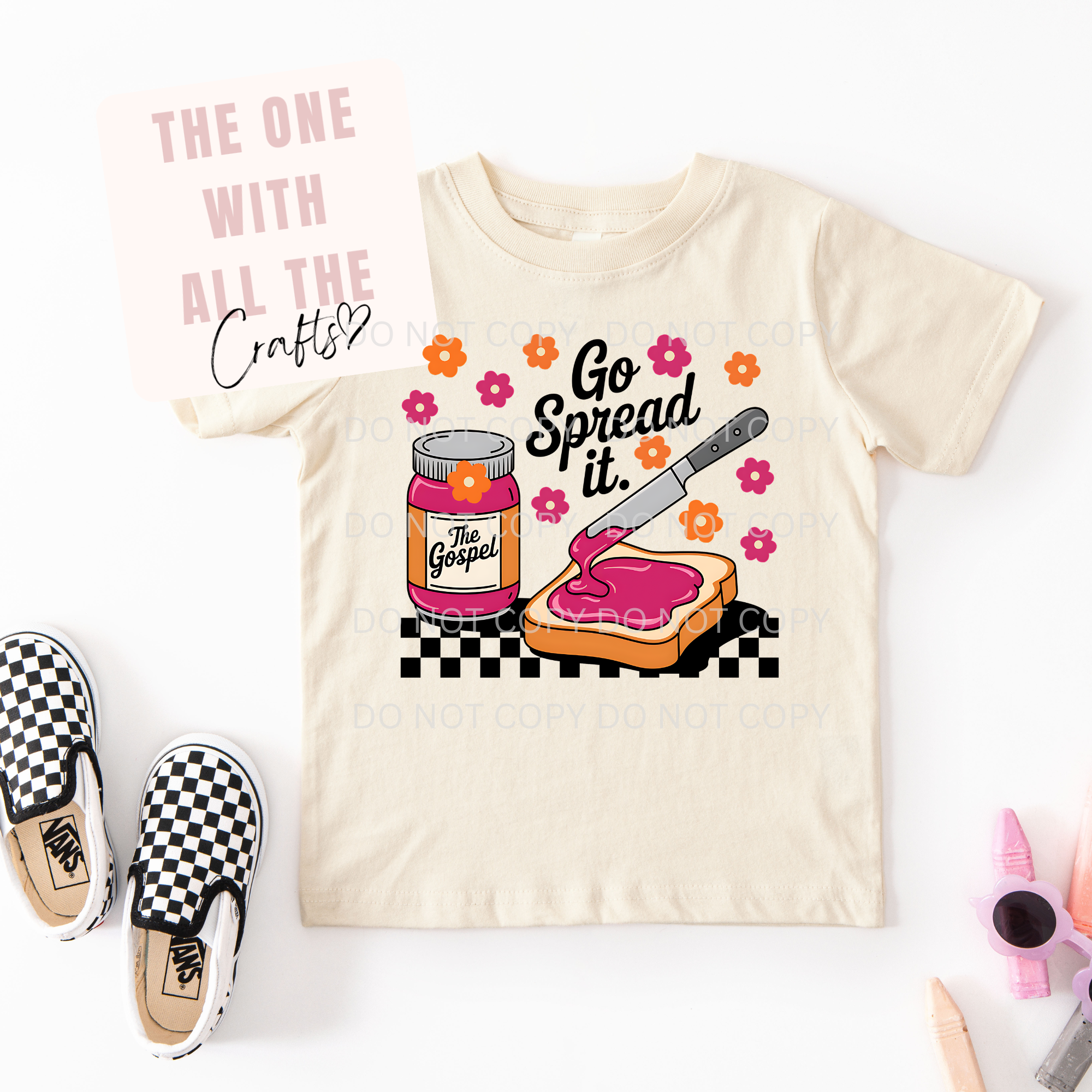Beige t-shirt with a graphic design of a jar of jelly, knife, and toast, accompanied by text, on a white background.