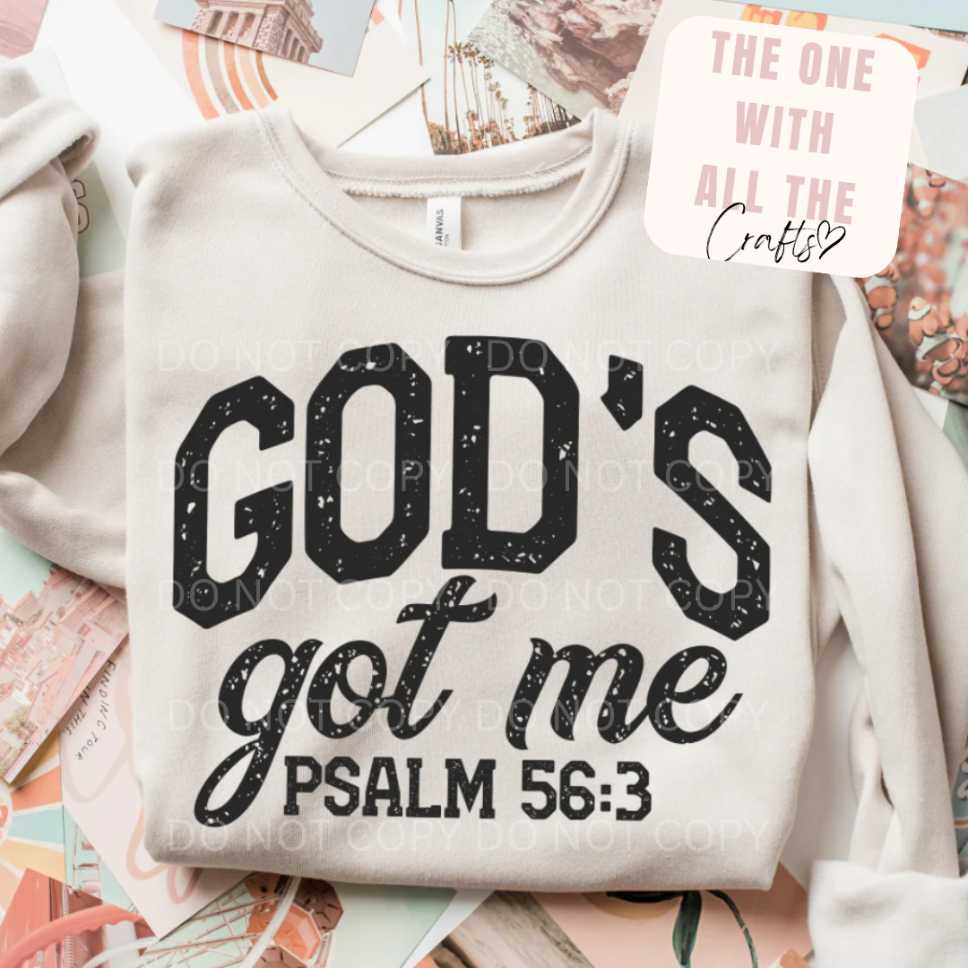 White sweatshirt with 'God's got me Psalm 56:3' text on a colorful surface.