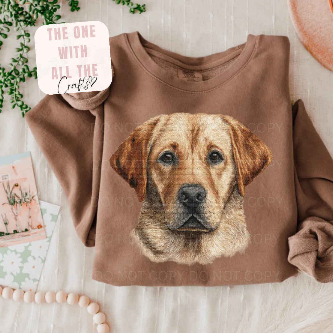 Brown sweatshirt with a dog's face design on a light wooden surface.