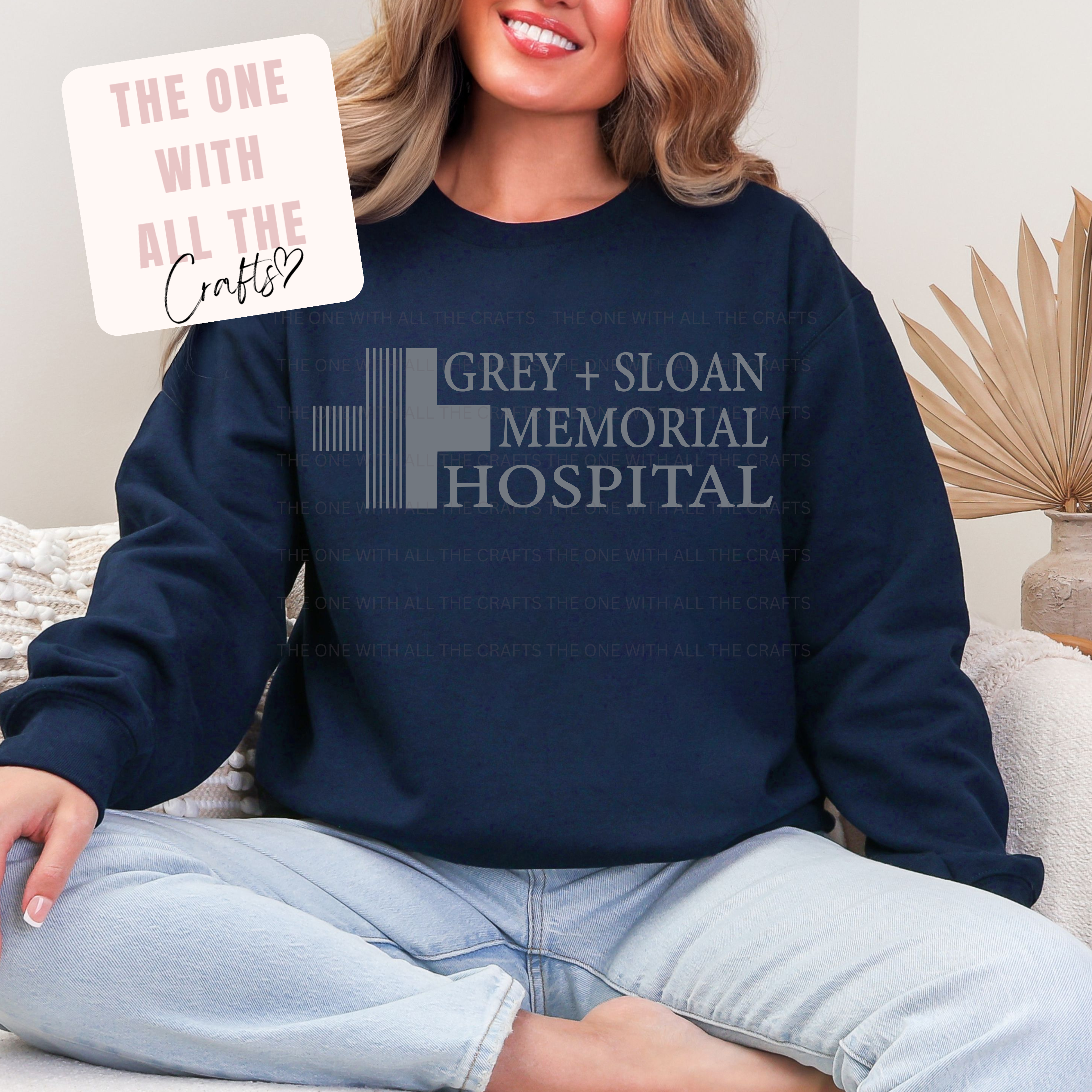 Person wearing a navy sweatshirt with 'Grey Sloan Memorial Hospital' text, sitting on a couch.