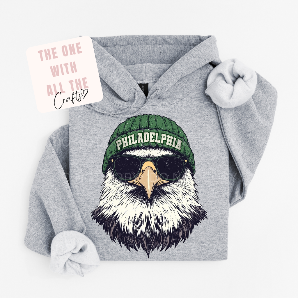 Gray hoodie with an eagle design wearing a green 'Philadelphia' beanie on a white background