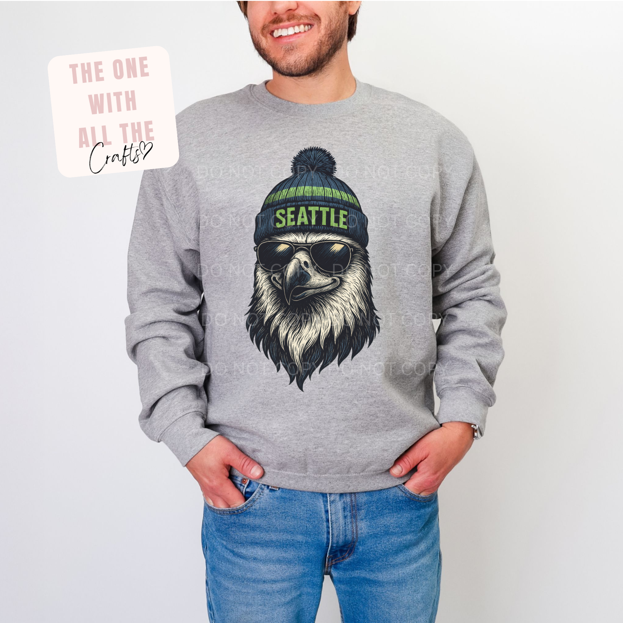 Person wearing a gray sweatshirt with a graphic of an eagle wearing sunglasses and a 'Seattle' beanie.