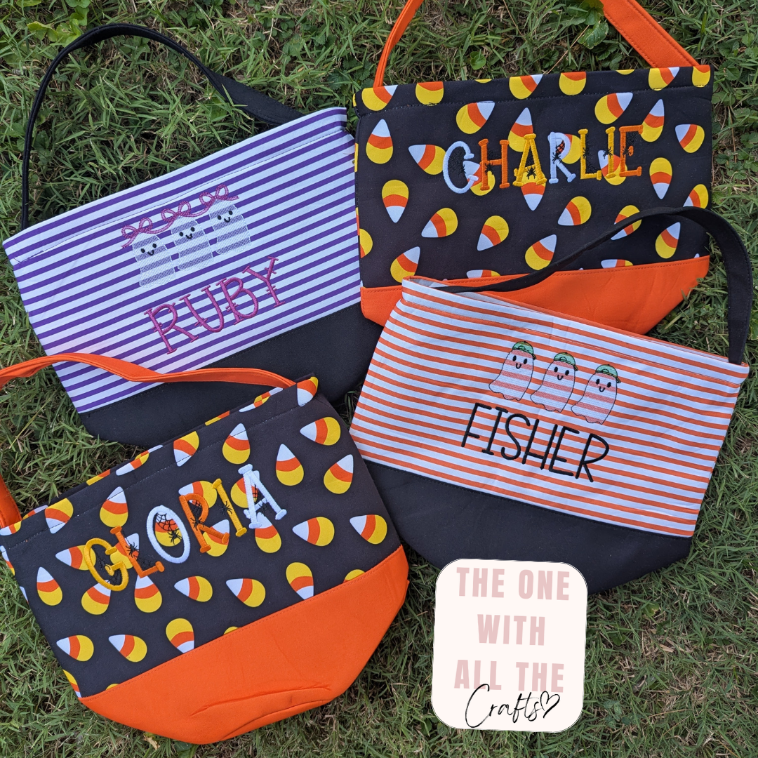 Four personalized Halloween-themed crossbody purses arranged on green grass. The bags feature different designs: purple and white stripes with 'RUBY' embroidery, black with orange/yellow candy corn and 'CHARLIE' embroidery, orange and white stripes with 'FISHER' embroidery, and black with orange/yellow candy corn and 'Gloria' embroidery.