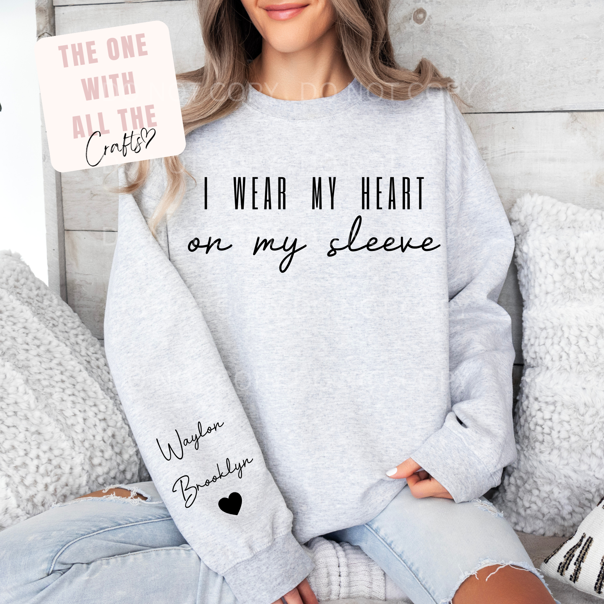 Person wearing a gray sweatshirt with text and a heart design, sitting on a couch.