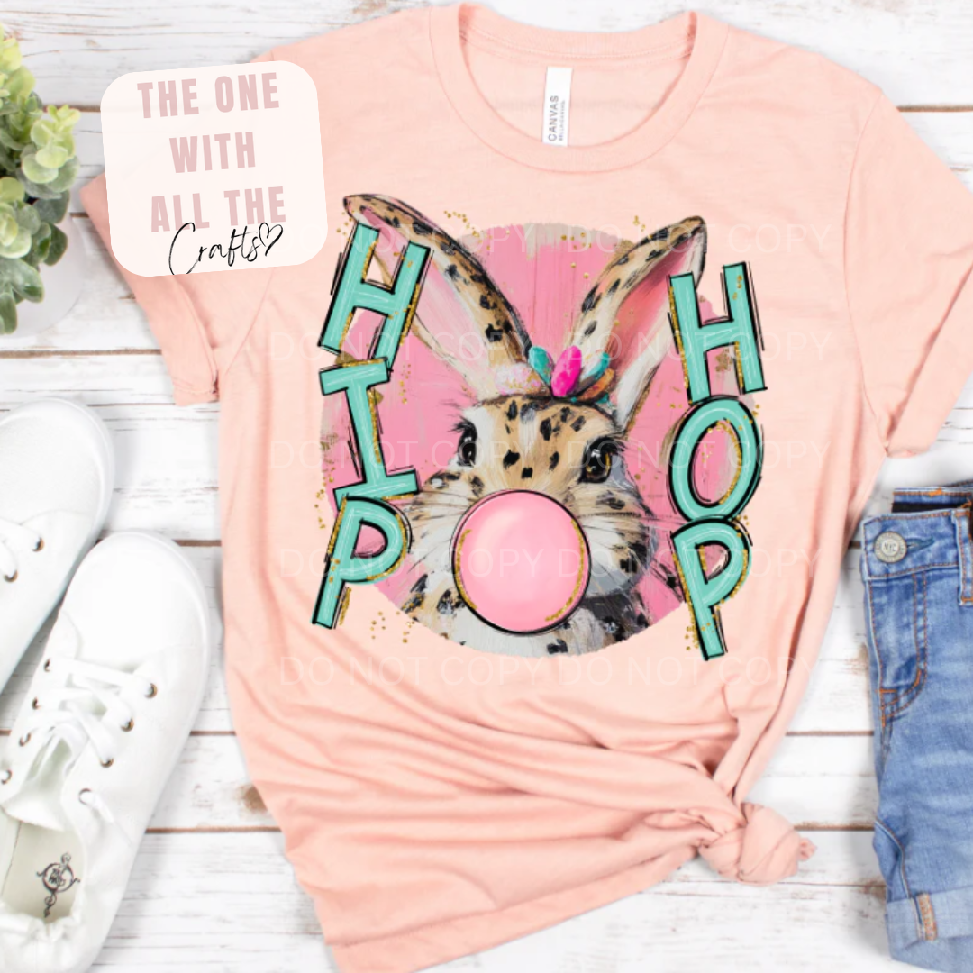 Pink t-shirt with a bunny graphic and 'HIP HOP' text on a wooden surface.