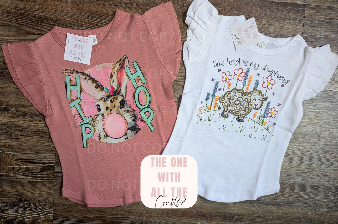 Two children's t-shirts with graphic designs on a wooden surface