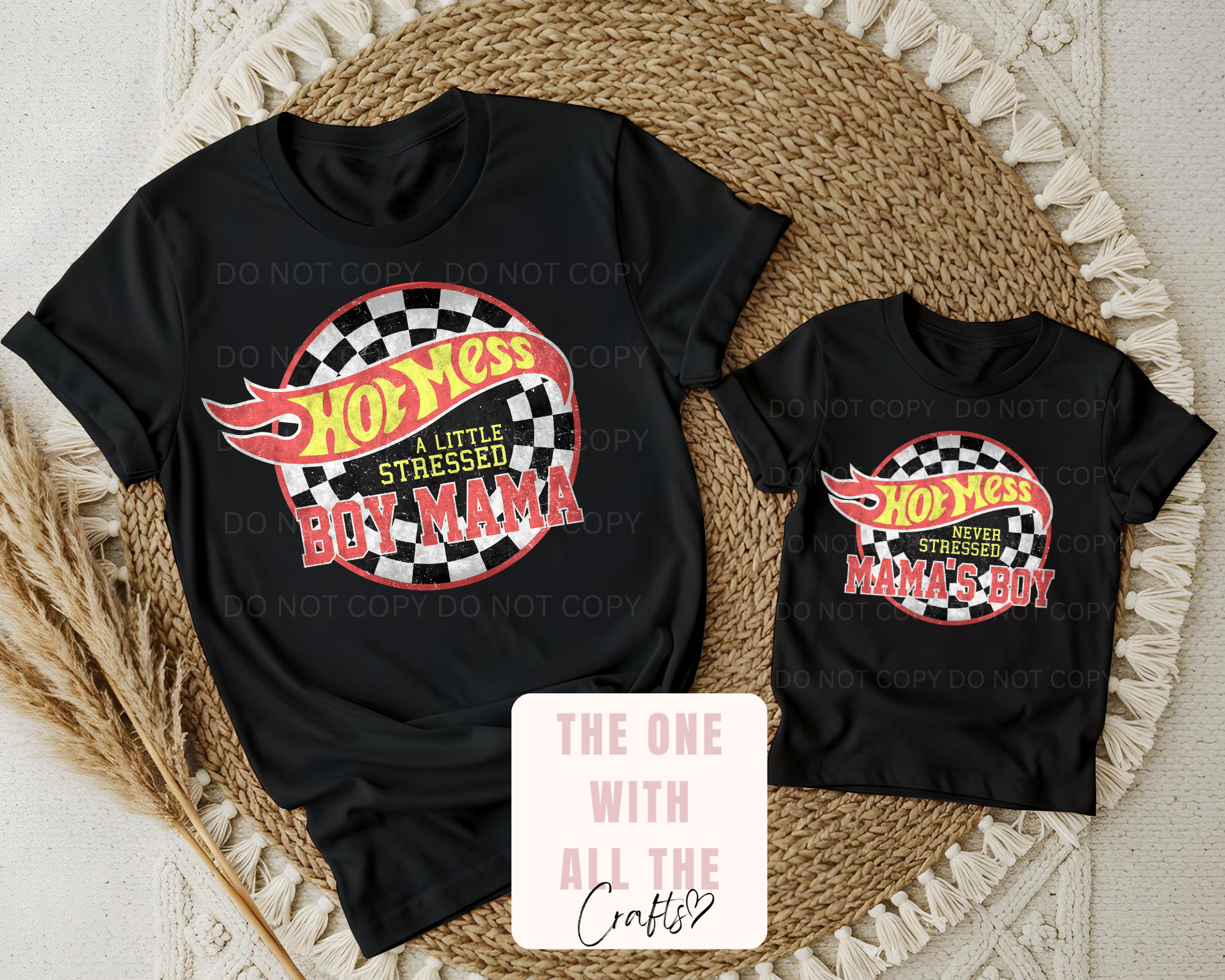 Two black t-shirts with colorful graphics and text on a textured surface.