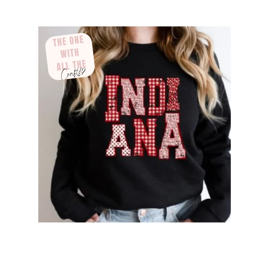 Black sweatshirt with 'INDIANA' in red checkered letters worn by a person.