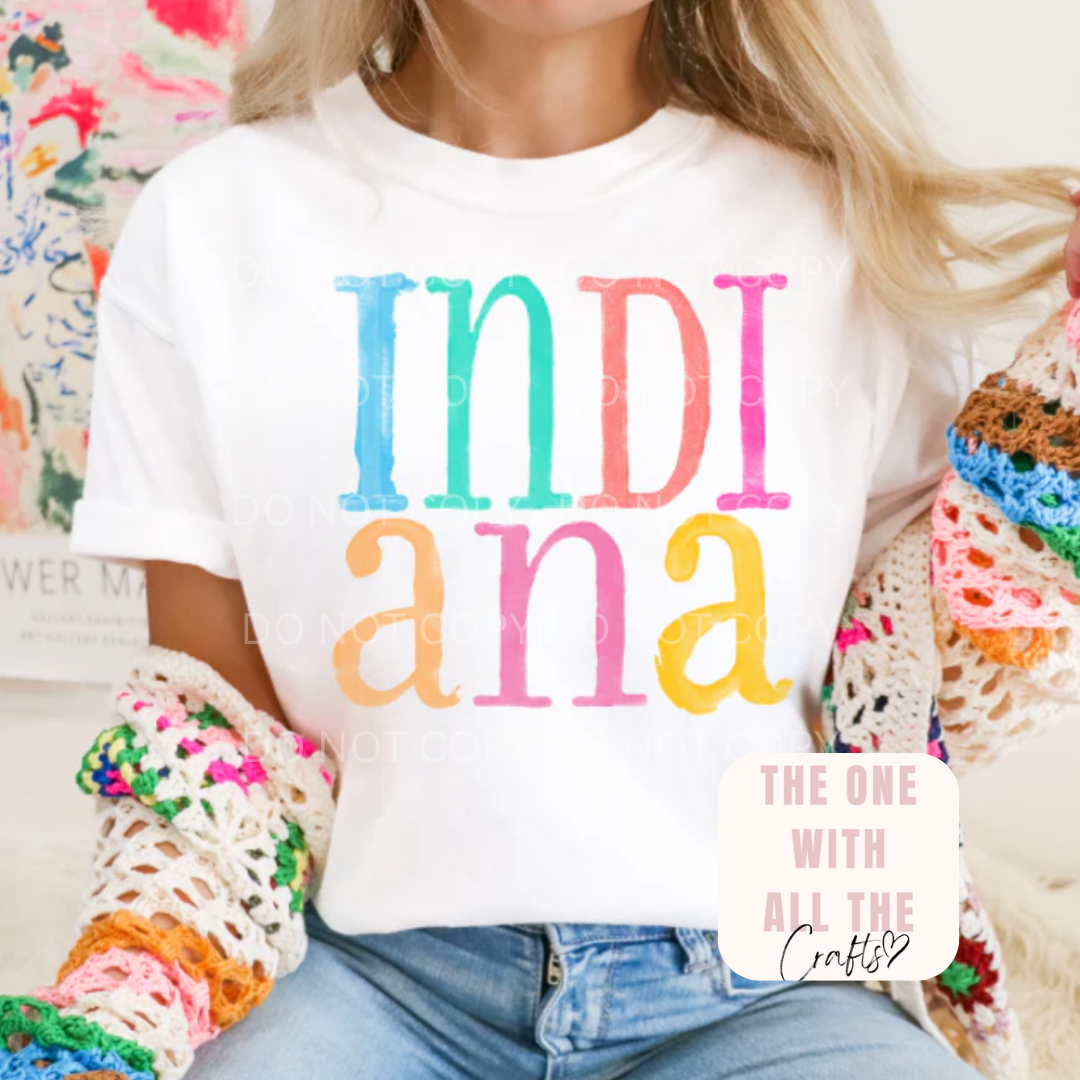Person wearing a white t-shirt with 'INDIANA' in colorful letters and text.