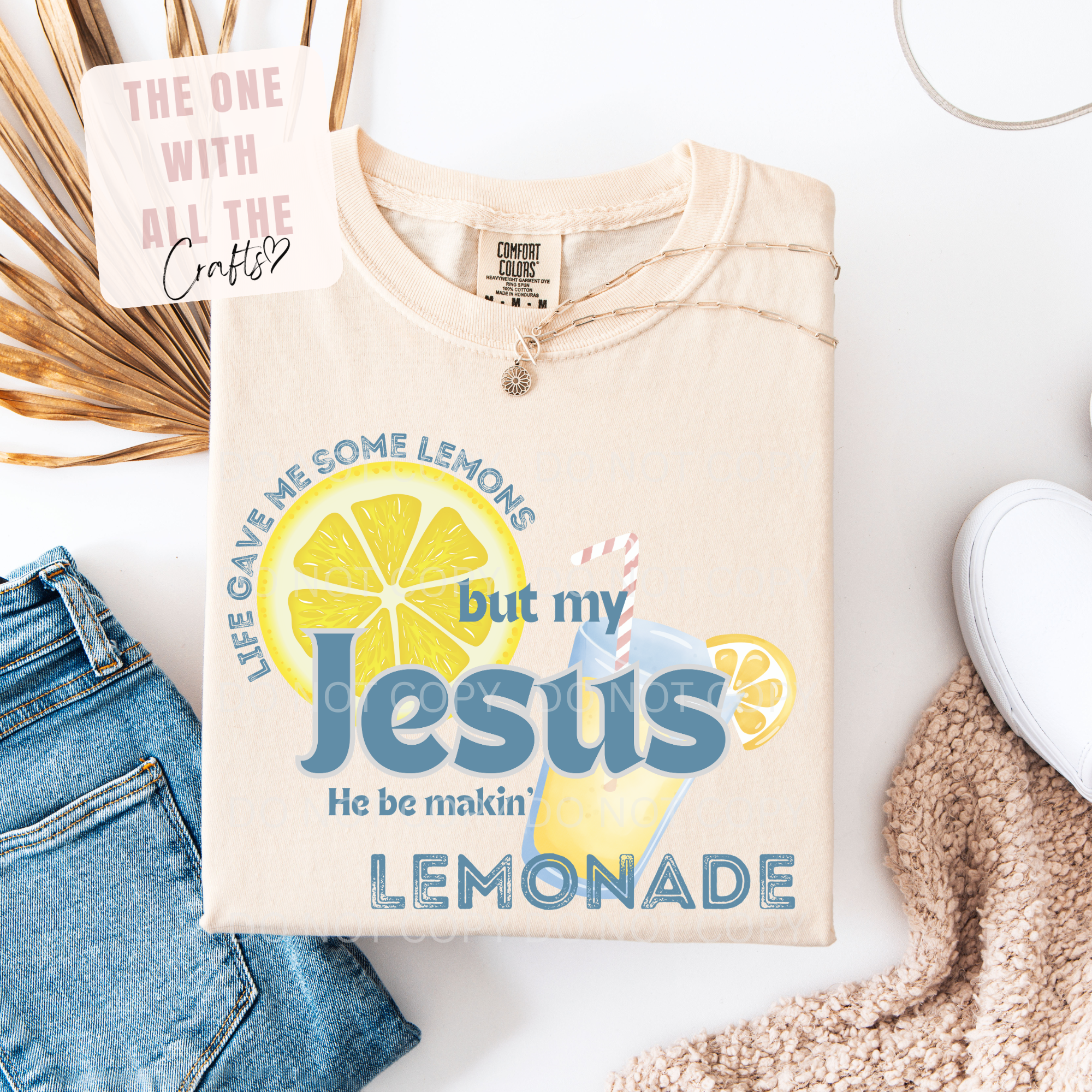 Beige sweatshirt with lemon-themed design and text on a white surface with denim jeans and a white sneaker.