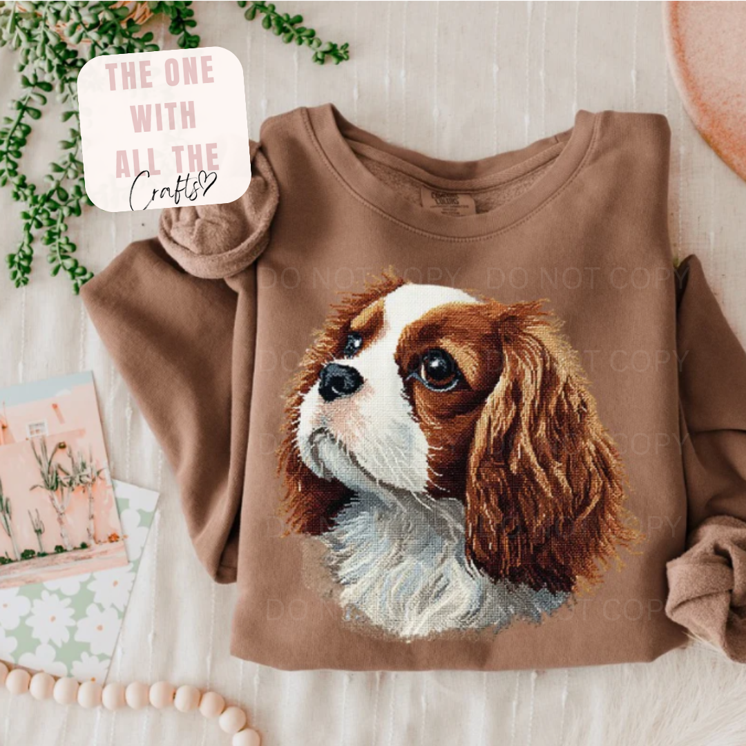 Brown sweatshirt with a dog illustration on a light wooden surface.