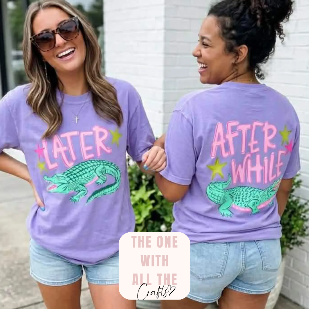 Two women wearing matching purple t-shirts with a graphic of an alligator and text, standing outdoors.