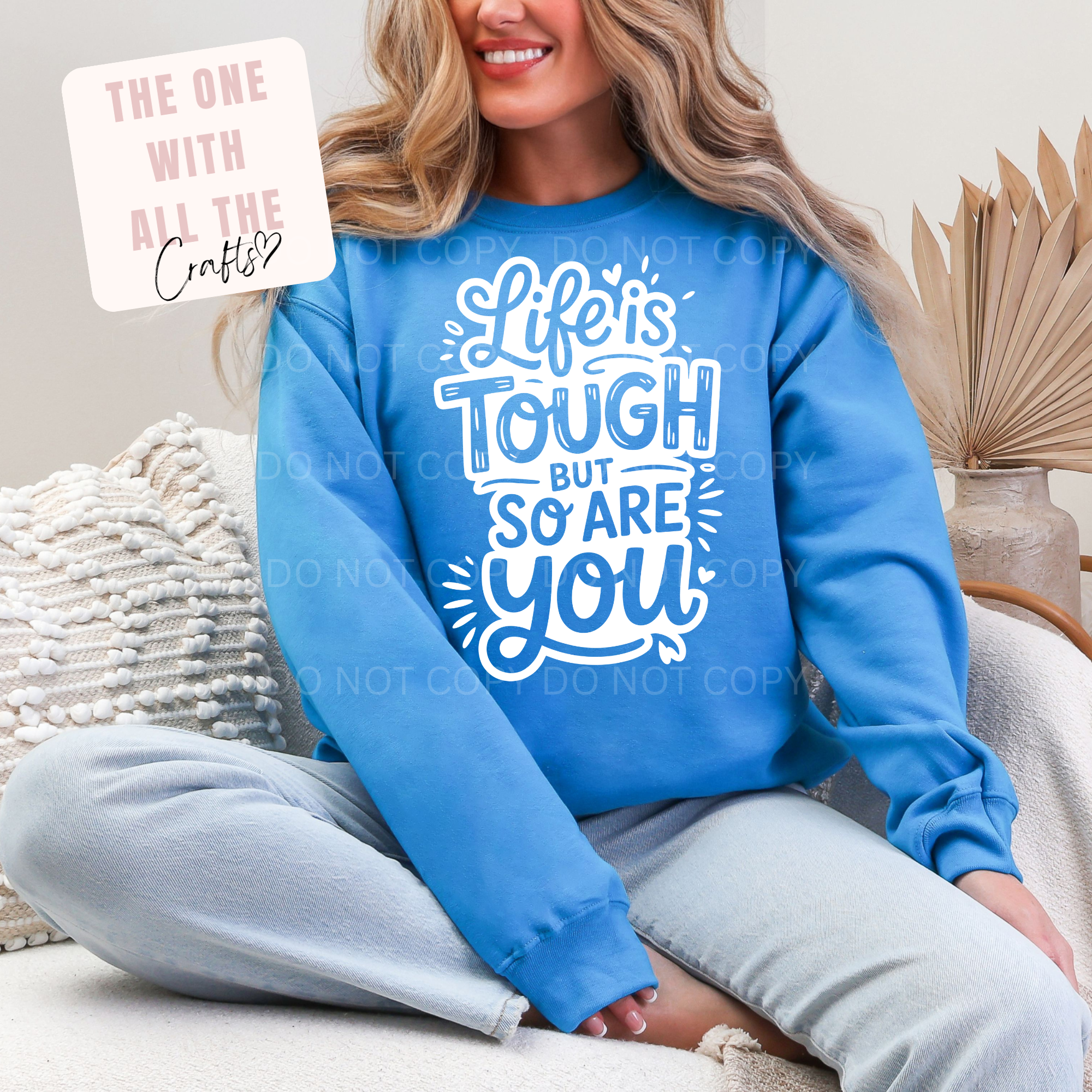 Person wearing a blue sweatshirt with 'Life is tough but so are you' text, sitting on a couch.