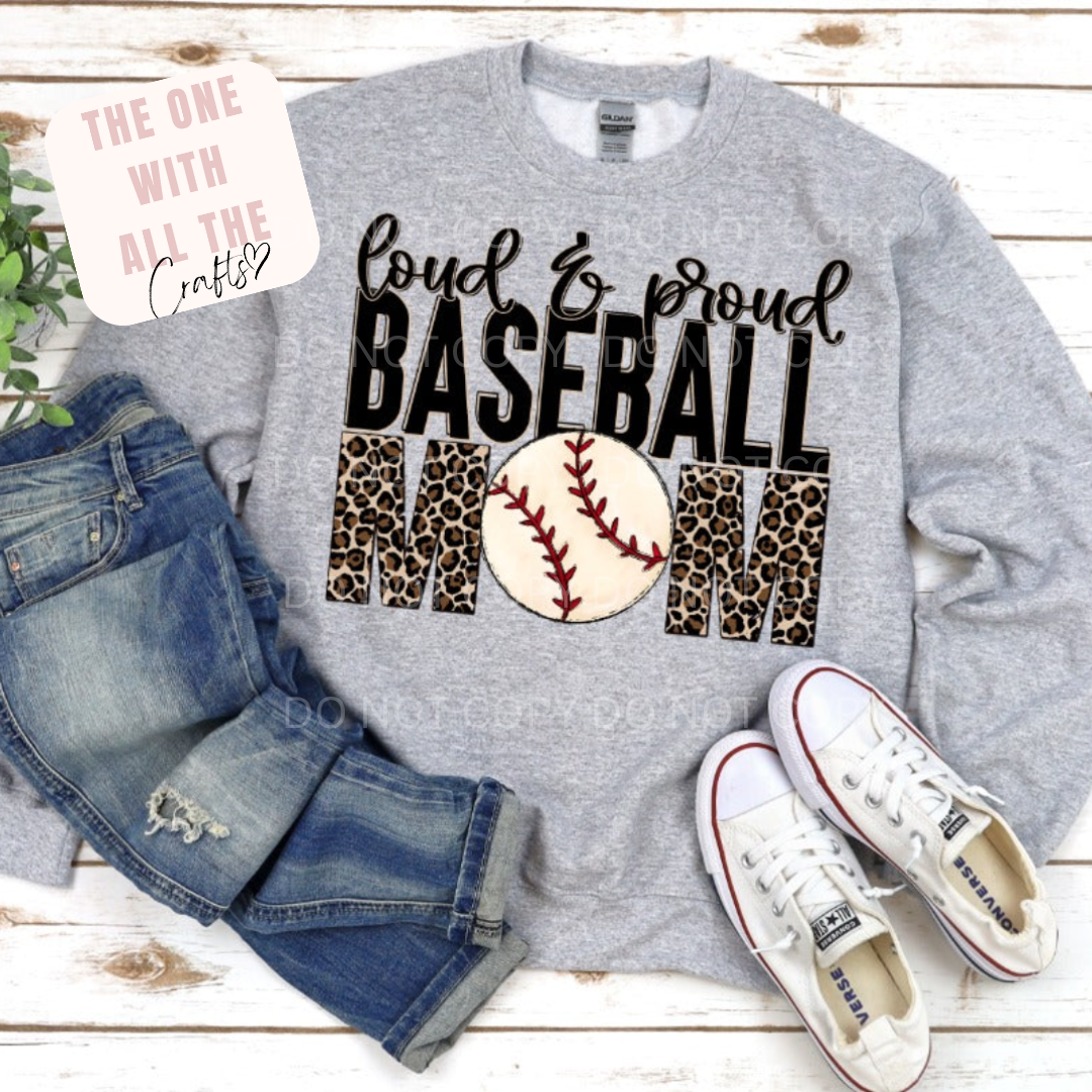 Gray sweatshirt with 'Loud & Proud Baseball Mom' text and baseball graphic, paired with jeans and sneakers on a wooden surface.