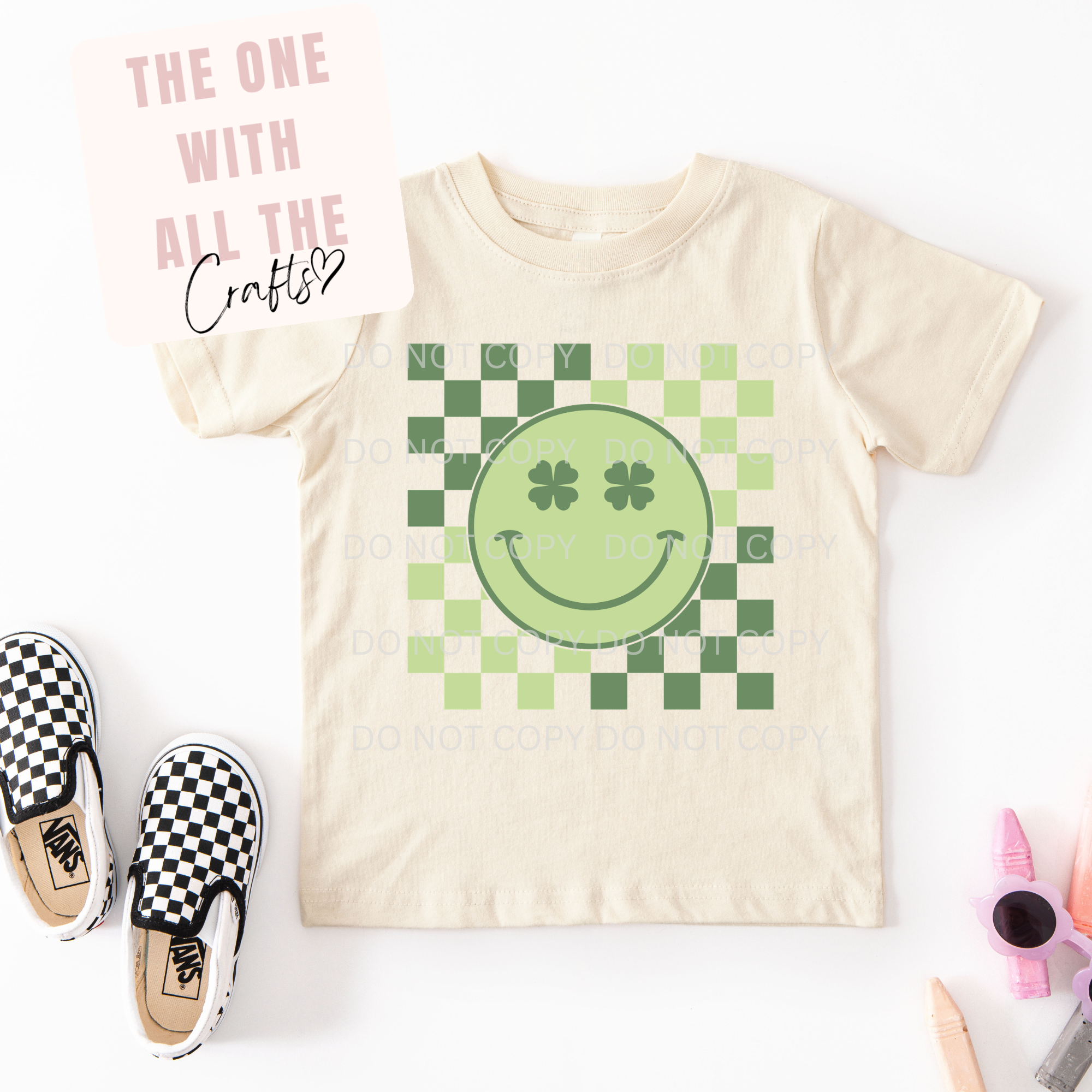 Beige t-shirt with green smiley face design on a white background