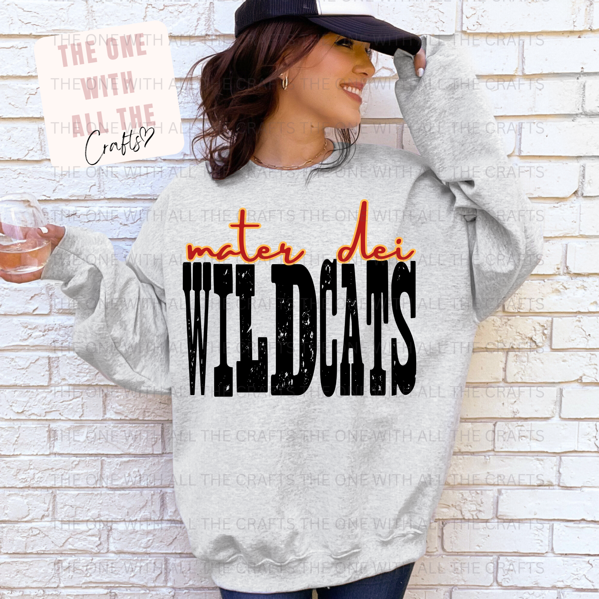 Person wearing a gray hoodie with 'mater dei WILDCATS' text against a light brick wall.