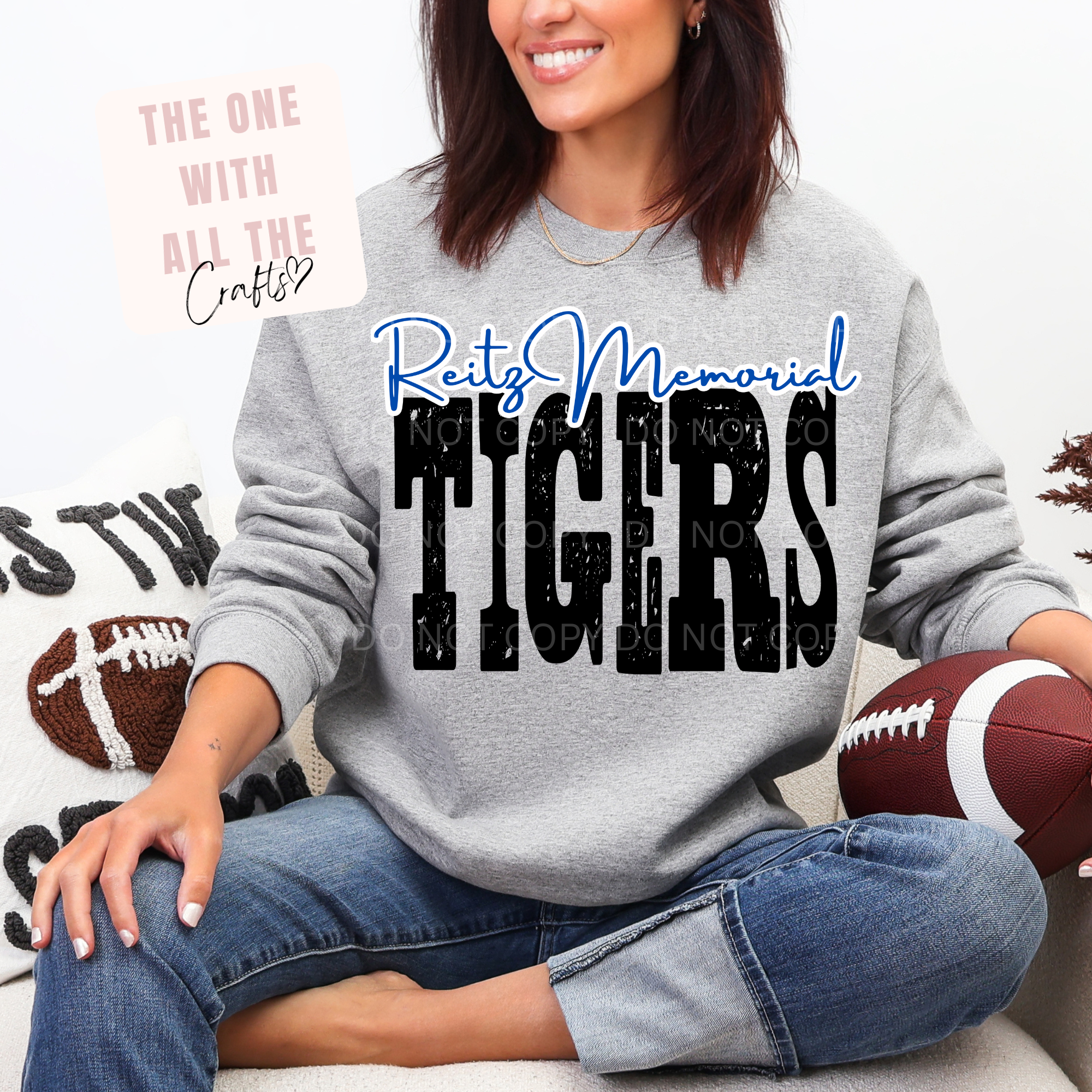 Person wearing a gray sweatshirt with 'Reitz Memorial Tigers' text, holding a football, sitting on a couch.