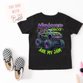Black t-shirt with monster truck graphic and text, paired with checkered shoes on a white background.