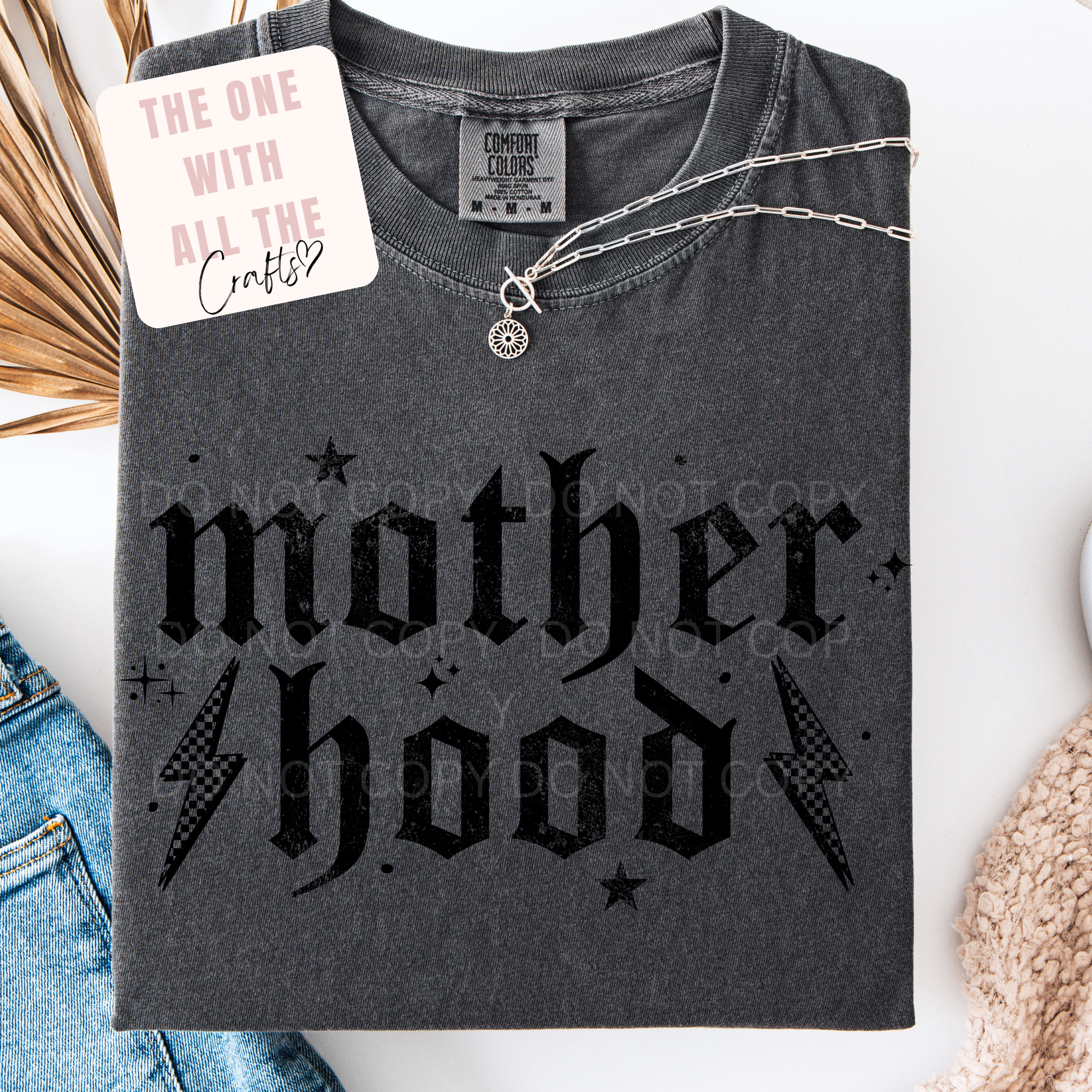 Gray t-shirt with 'motherhood' text and necklace on a white background
