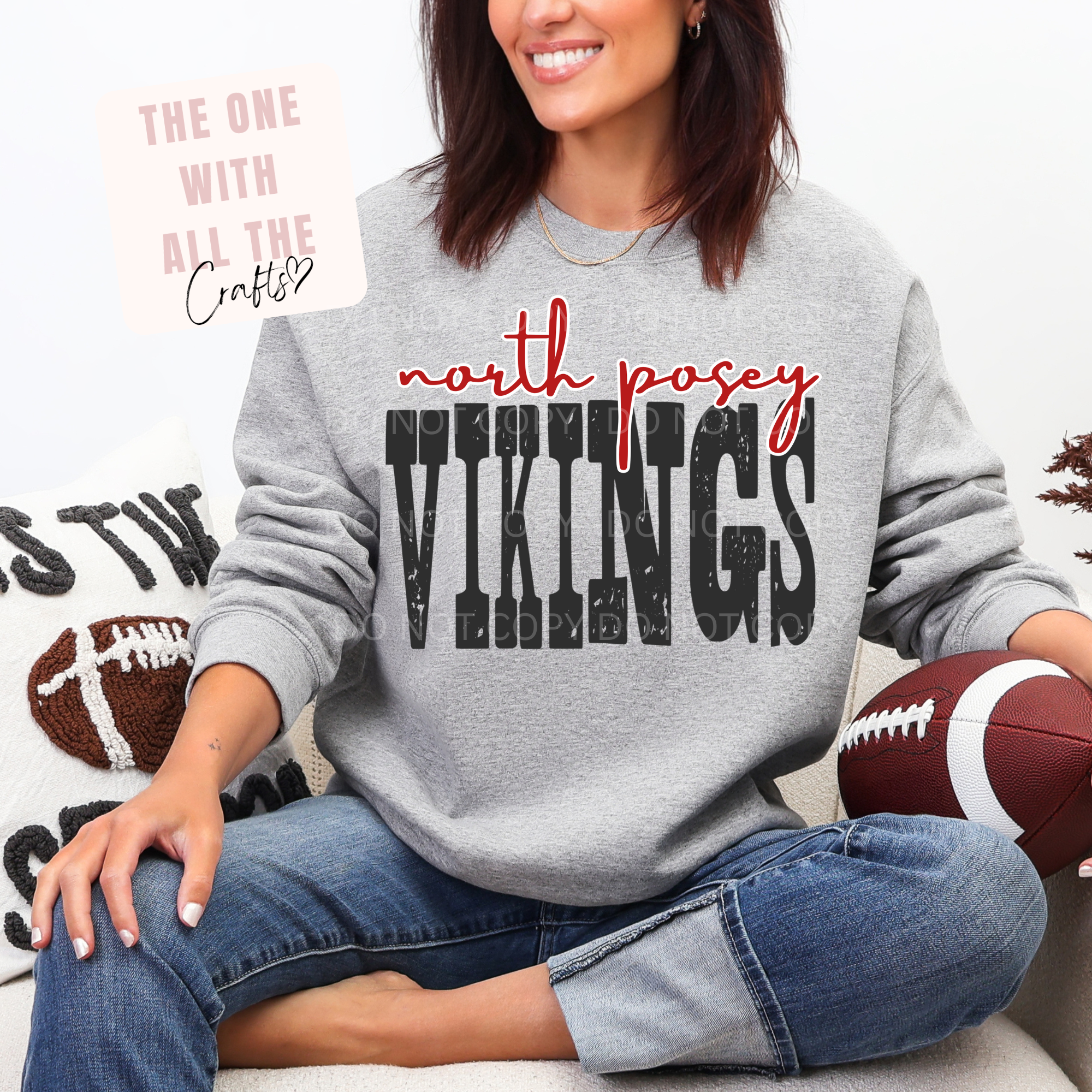 Person wearing a gray sweatshirt with 'north posey vikings' text, holding a football, sitting on a couch.