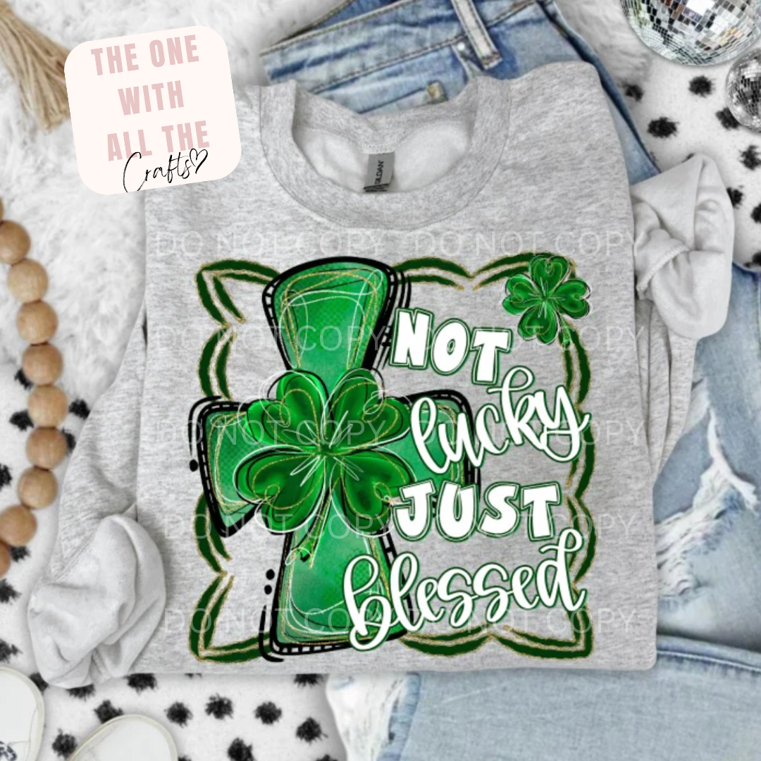 Gray sweatshirt with green cross and shamrock design, text 'Not lucky just blessed', on a white background.
