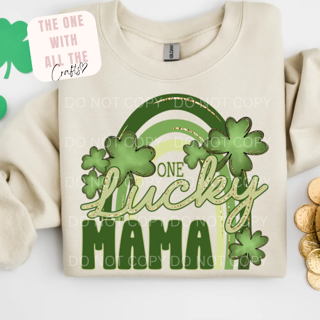 Beige sweatshirt with 'One Lucky Mama' design featuring clovers and a rainbow on a white background.
