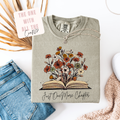Folded sweatshirt with floral design and text on a white surface with denim jeans and decorative elements.