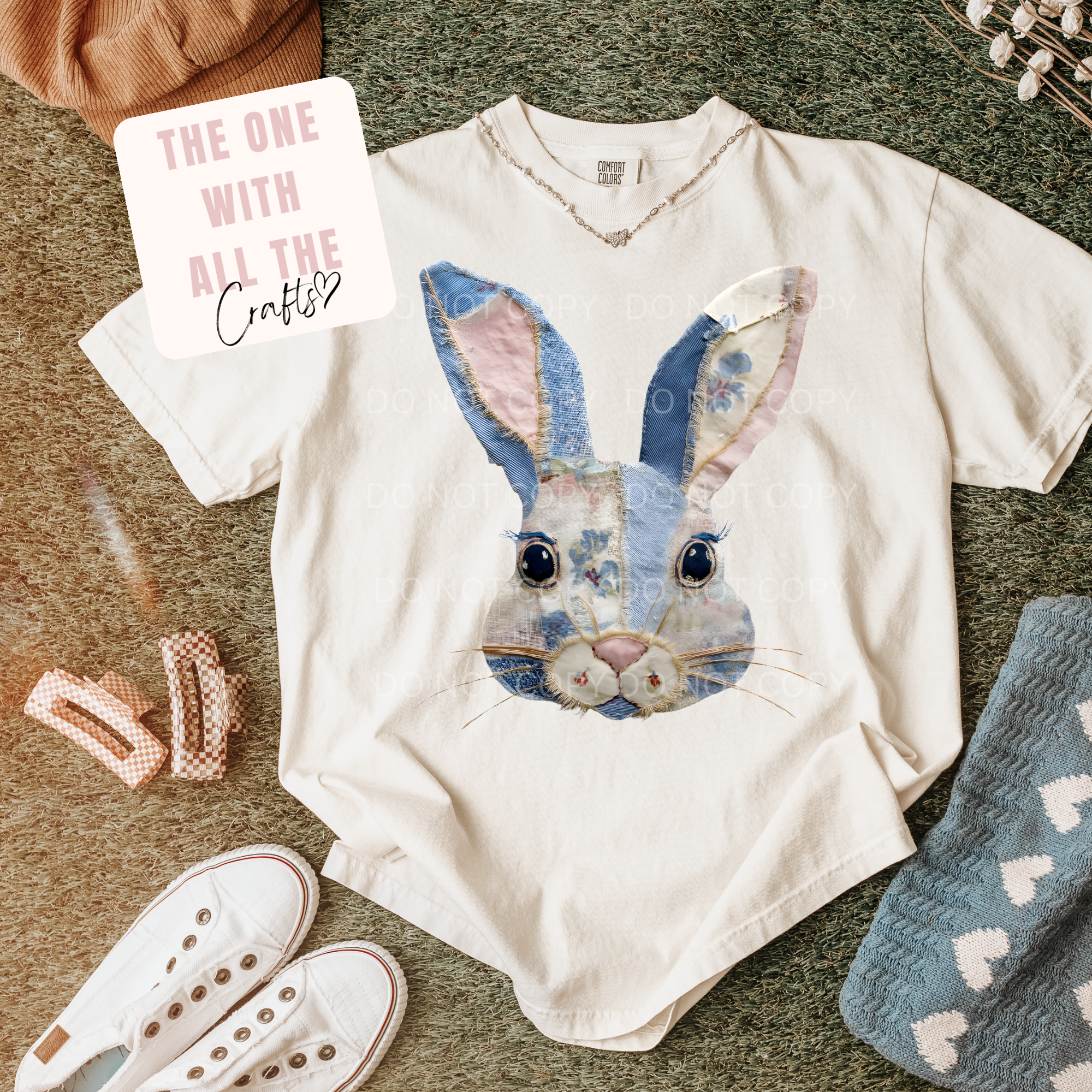 White t-shirt with a rabbit design, socks, and accessories on a textured surface.