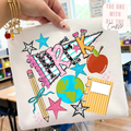 Hand holding a tshirt with colorful school-themed designs in a classroom setting.