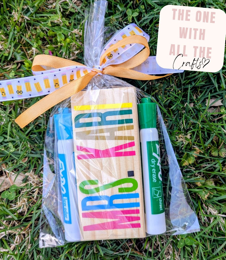 Packaged craft supplies with colorful markers and a dry erase marker on grass, labeled 'The One With All The Crafts'.
