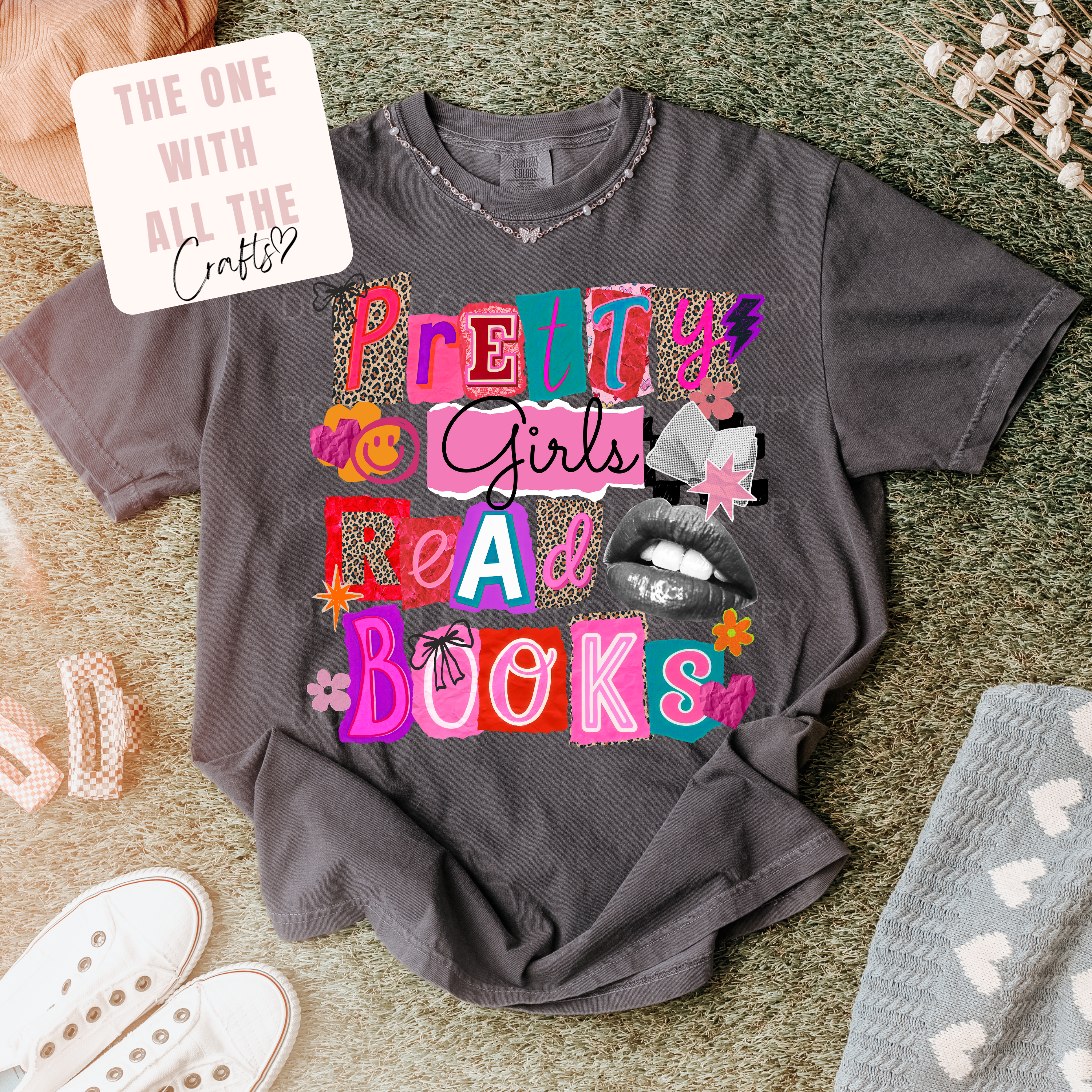 Gray t-shirt with colorful text 'Pretty Girls Read Books' on a textured surface.