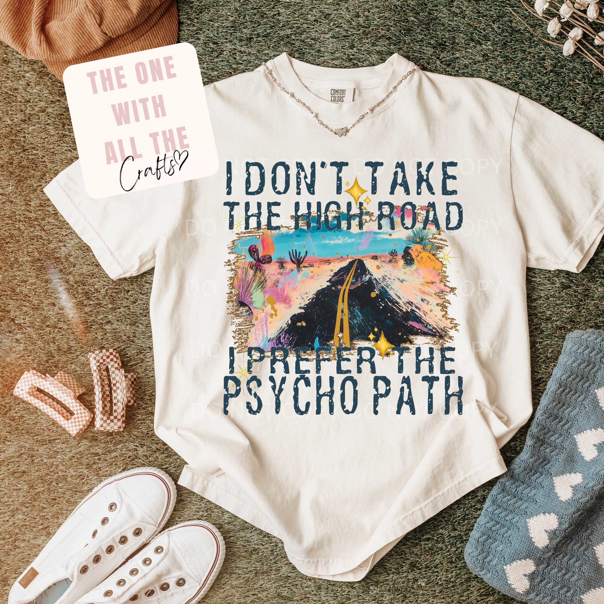 White t-shirt with graphic design and text on a surface with accessories.